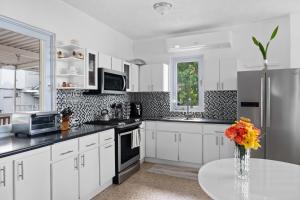 a kitchen with white cabinets and a vase of flowers on a table at Lucky Luquillo Solar El Yunque & Beach Retreat - 360 Ocean & Rainforest Views in Fortuna