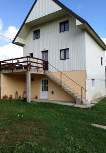 une grande grange blanche avec des escaliers sur le côté dans l'établissement Apartment Helena, à Žabljak