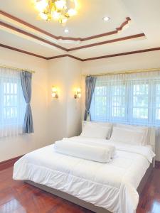 a large white bed in a room with windows at Huahinpoolvilla in Hua Hin