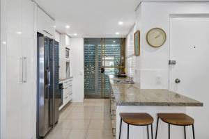 a kitchen with white walls and a counter with stools at Beachside Oasis-Walk to Alex Beach in Alexandra Headland