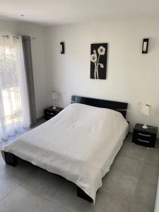 a bedroom with a large white bed with two lamps at Les arbousiers de Murateddu in Porto-Vecchio