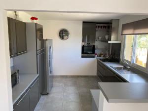 a large kitchen with gray cabinets and a large window at Les arbousiers de Murateddu in Porto-Vecchio