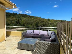 a wicker couch sitting on the balcony of a house at Les arbousiers de Murateddu in Porto-Vecchio