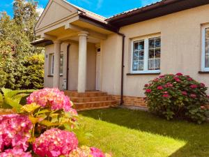 ein Haus mit rosa Blumen davor in der Unterkunft Sielanka Dom nad Morzem in Sławoszyno