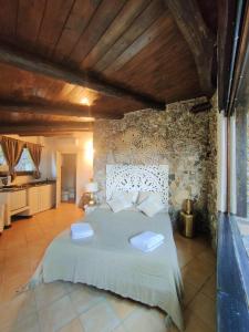 a bedroom with a large bed with a stone wall at Maison Du Reve Scario in Scario +103 photos
