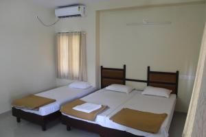 two twin beds in a room with a window at Anna Hotel in Trivandrum