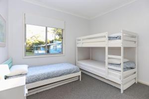 a bedroom with two bunk beds and a window at Lovely Pet Friendly Beach House in Hawks Nest