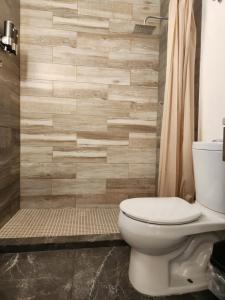 a bathroom with a toilet and a wooden wall at Casa Vacacional Amaia in Mazatlán
