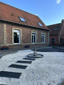 une cour avec une fontaine devant un bâtiment en briques dans l'établissement O coeur des Monts et Merveilles, à Wormhout