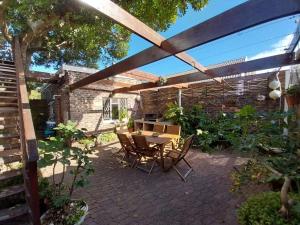 a patio with a table and chairs under a pergola at Bushmansriver Tree-House in Bushmans River Village