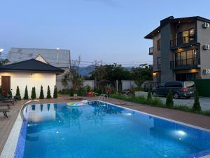 a large blue swimming pool next to a building at Villa Feel Georgia in Batumi