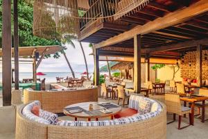 an outdoor restaurant with tables and chairs and the beach at Anantara Rasananda Koh Phangan Villas in Thong Nai Pan Noi