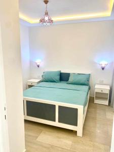 une chambre avec un lit dans une pièce blanche dans l'établissement ResidenceHbiba-Appart2-RDC, à Ḩammām al Ghazzāz