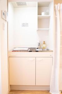 a small kitchen with white cabinets and a sink at 五月荘 Satsukiso in Osaka