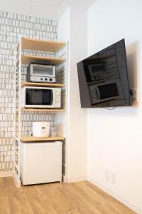 a kitchen with three microwaves and a tv on a wall at 五月荘 Satsukiso in Osaka