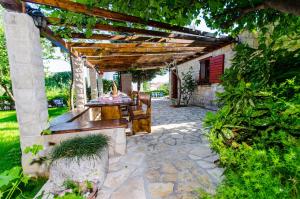 a patio with a table and chairs under a pergola at Villa Marcelina in Seget Vranjica