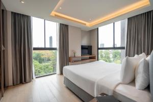 a bedroom with a large bed and large windows at Walton Suites Sukhumvit in Bangkok