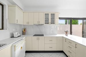 una cucina bianca con mobili bianchi e una finestra di Luxe Ensuite Queen Room - Close to Stations & Shops a Bankstown