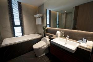 a bathroom with a sink and a toilet and a bath tub at Walton Suites Sukhumvit in Bangkok