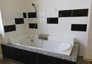 e bagno con vasca e piastrelle bianche e nere. di Maison de 100m2 au cœur d'une pension équestre Les Sabots de Nina a Marcollin Altre 8 foto
