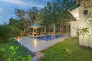 a swimming pool with an umbrella in a yard at SaffronStays Dalewal Jungle Lodge, Hoshiarpur in Hoshiārpur