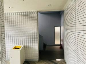 a bathroom with a white tiled wall and a hallway at ラパルフェドアンテイエール in Matsuyama