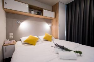 een slaapkamer met een wit bed met gele kussens bij Holiday Home Trend in Donji Zagon +55 foto's