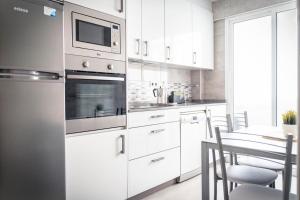 a kitchen with white cabinets and a table with chairs at Apartamento Estrela in Ferrol