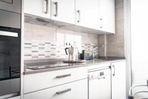 a kitchen with white cabinets and a mixer on the counter at Apartamento Estrela in Ferrol +26 photos