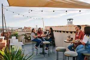 a group of people sitting at tables on a rooftop patio at Toc Hostel Granada in Granada