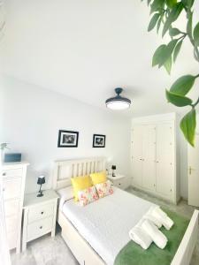 a bedroom with a white bed with yellow pillows at Apartamento Atlántico in Rota +45 photos