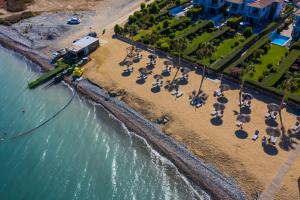 an aerial view of a beach with chairs and umbrellas at Atlantis Gardens in Mazotos