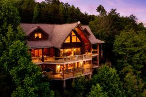 a large log cabin in the middle of the trees at Great Alpine - 4 KingSuites- December Deals-Views-Hot Tub-FirePit-GameRm in Gatlinburg