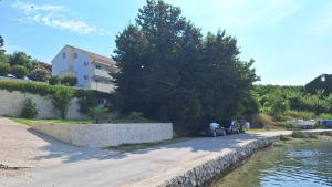 a house and a retaining wall next to a river at Apartments Nikola Caska in Novalja