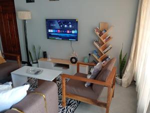 a living room with two chairs and a tv on the wall at Sinana Escapes - Arusha in Arusha