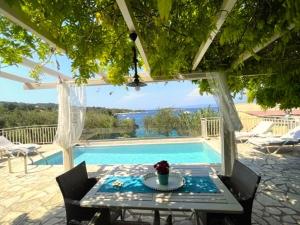 a table and chairs next to a swimming pool at Mare Villa Ciel - by Portogaios Paxos Superior Living in Gaios