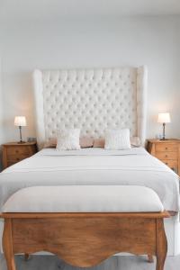 a large bed with a large white headboard and two tables at Sunrise & Pool Mairena Metro in Mairena del Aljarafe