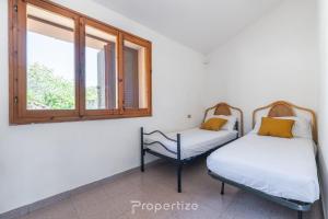 two beds in a room with a window at L'oasi Panoramica by Propertize - Olbia in Pittulongu