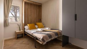 a bedroom with a bed with yellow pillows and a window at Terra Park Phalaris in Novalja