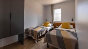 two beds in a small room with a window at Terra Park Phalaris in Novalja