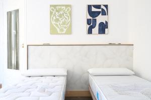 two beds in a bedroom with art on the wall at Tradición y modernidad Casa de pueblo junto al mar in Puerto de Sagunto