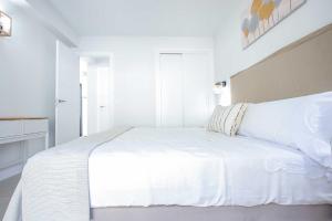 a white bedroom with a white bed and a window at Linda Vista Beach Apartment in Marbella +22 photos