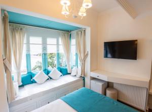 a bedroom with a window seat with a flat screen tv at Kairos Hotel in Siğacık