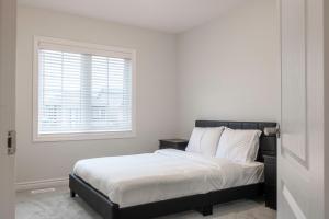 a bedroom with a bed with white sheets and a window at 10 Minutes From The Falls in Thorold