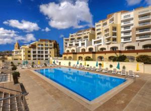 une grande piscine devant certains bâtiments dans l'établissement Monita 113, Seaside Apartment with Access to Pool and Pleasant Views, à Marsaskala