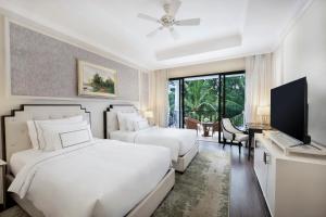 a bedroom with two beds and a flat screen tv at Melia Vinpearl Phu Quoc in Phu Quoc