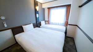 大阪Toyoko Inn Shin-osaka Higashi-mikuni Ekimae的小房间设有两张床和窗户