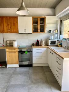a kitchen with white cabinets and a stove top oven at Nicole's Cave Studio in Pylos +24 photos