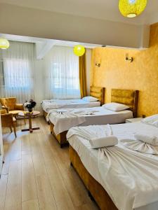 une chambre d'hôtel avec quatre lits et un canapé dans l'établissement AVRASYAQUEEN HOTEL, à Istanbul