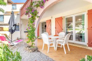 a patio with a table and chairs and an umbrella at Appartement aux Aloès in Cerbère